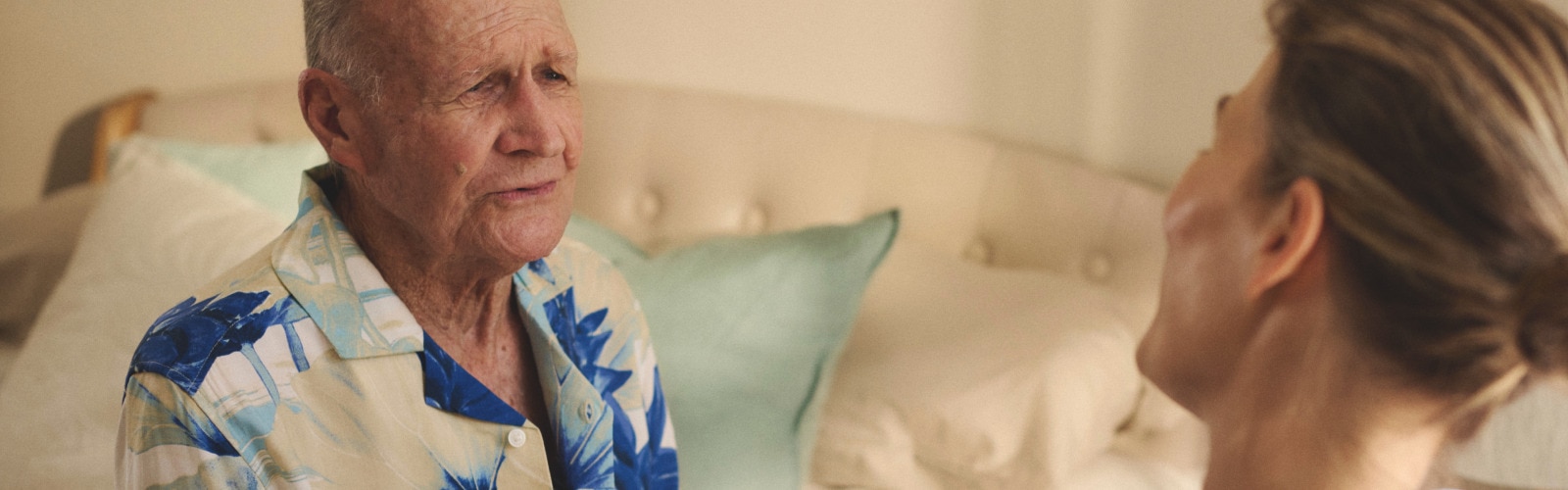 A professional caregiver helps a nursing home resident button his shirt