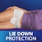 A woman in a purple t-shirt is lying down while wearing TENA underwear. A text underneath the image reads "Lie down protection"
