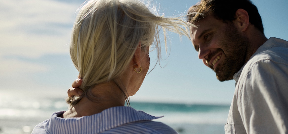 Caregiver con una donna sorridente sulla spiaggia