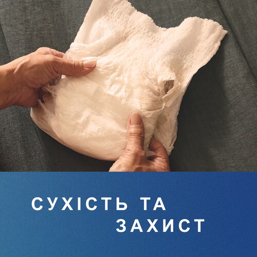 Людина тримає в руках труси-підгузки TENA.