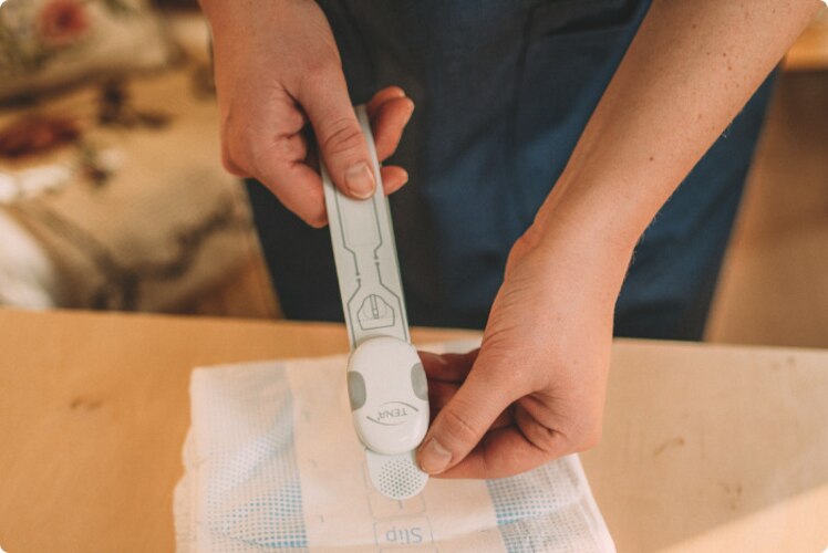 A professional caregiver applies the TENA SmartCare Change Indicator to the front of a TENA absorbent product