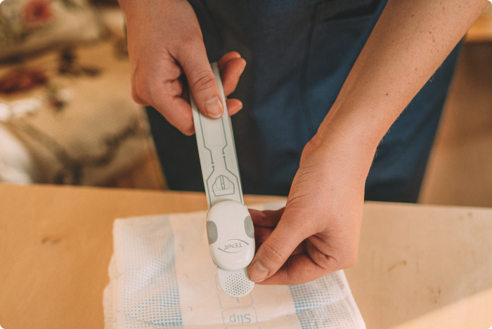 Un soignant professionnel applique TENA SmartCare Change Indicator sur un produit absorbant TENA