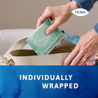Ze plaatst het apart verpakte TENA Discreet verband in haar handtas
