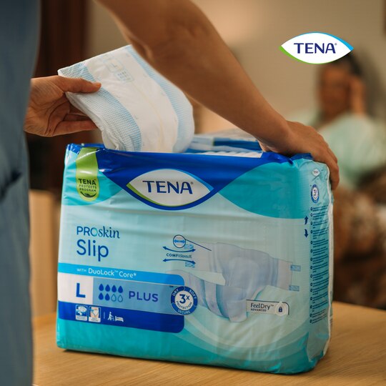 Main sortant le produit TENA Slip ProSkin du paquet