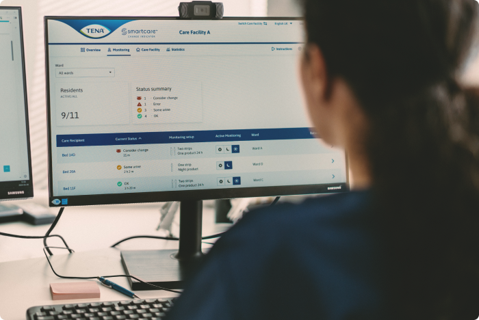 A professional caregiver reads statistics and reports generated by the TENA SmartCare Change Indicator. These can be used to adapt care as residents’ needs change.