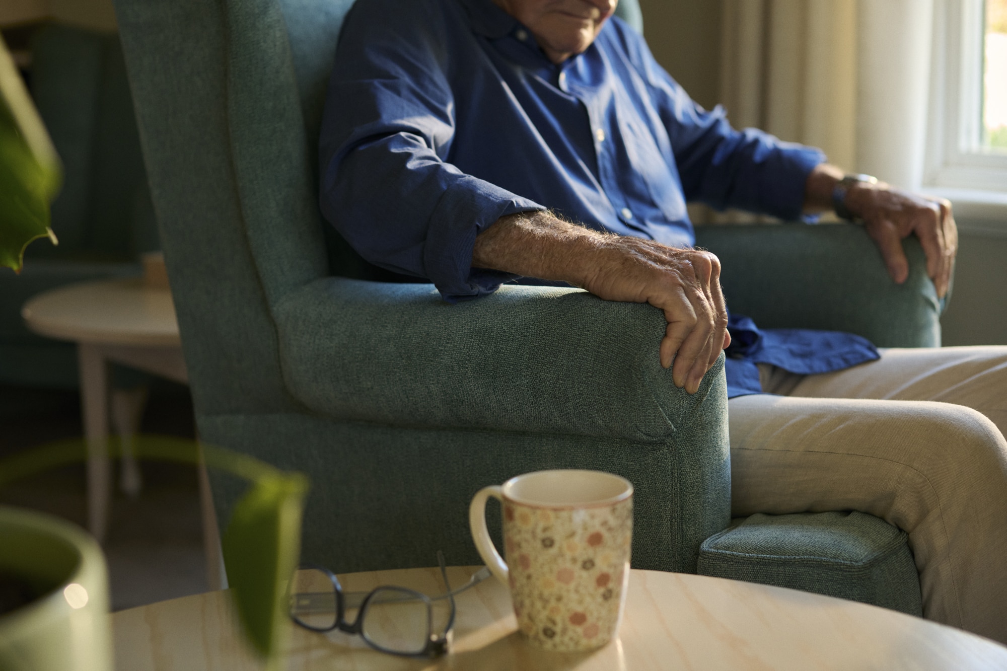 Een oudere mannelijke bewoner zit op een stoel in een woonzorgcentrum