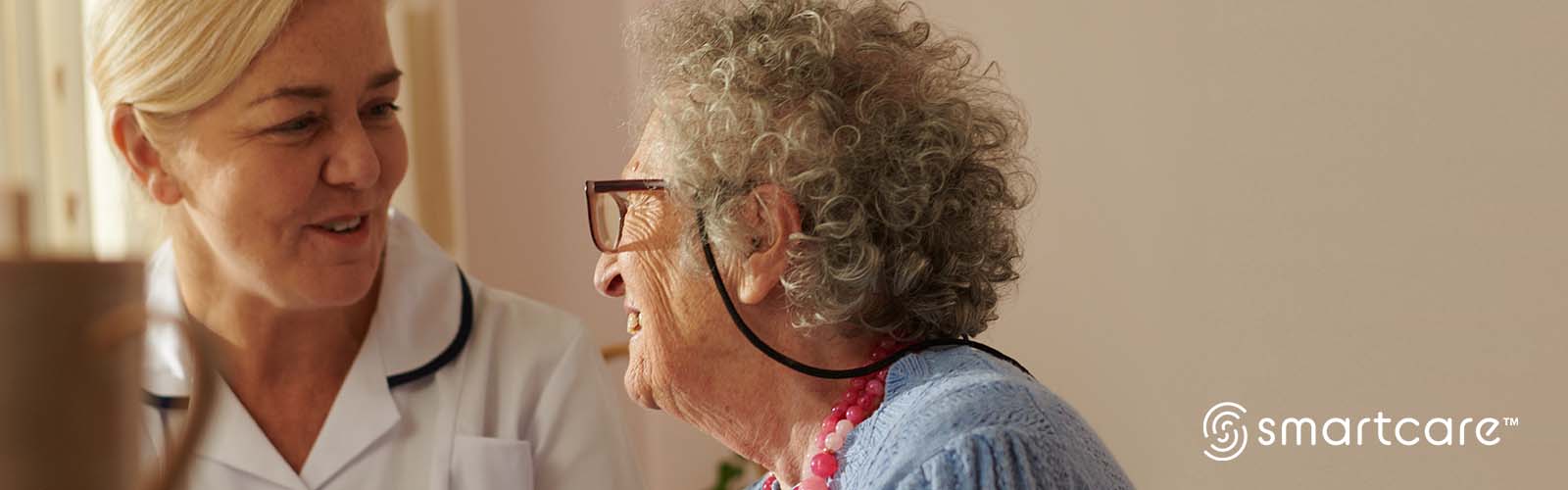 Eine weibliche Pflegefachkraft und eine ältere Bewohnerin unterhalten sich im Pflegeheim