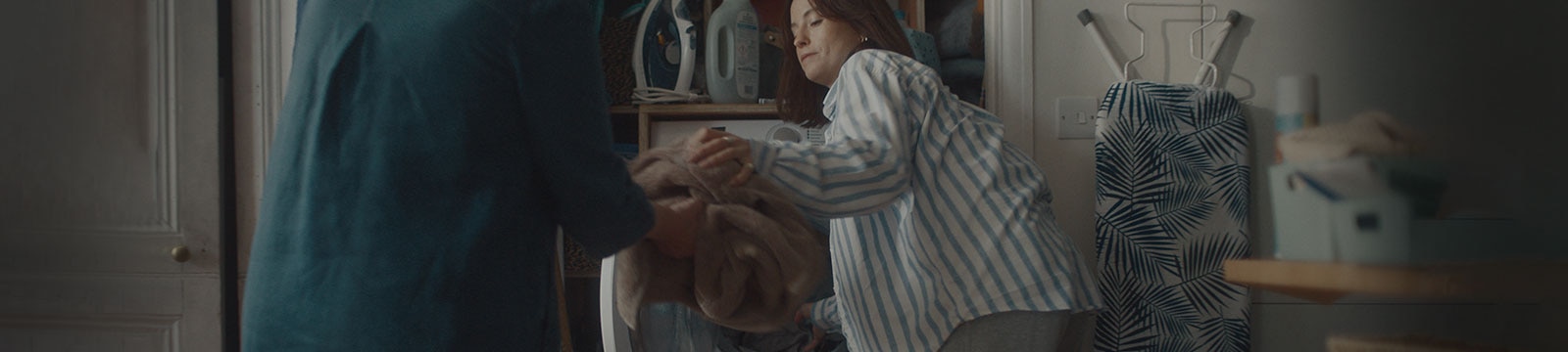 Una mujer saca la colada de la lavadora y se la da a su madre.