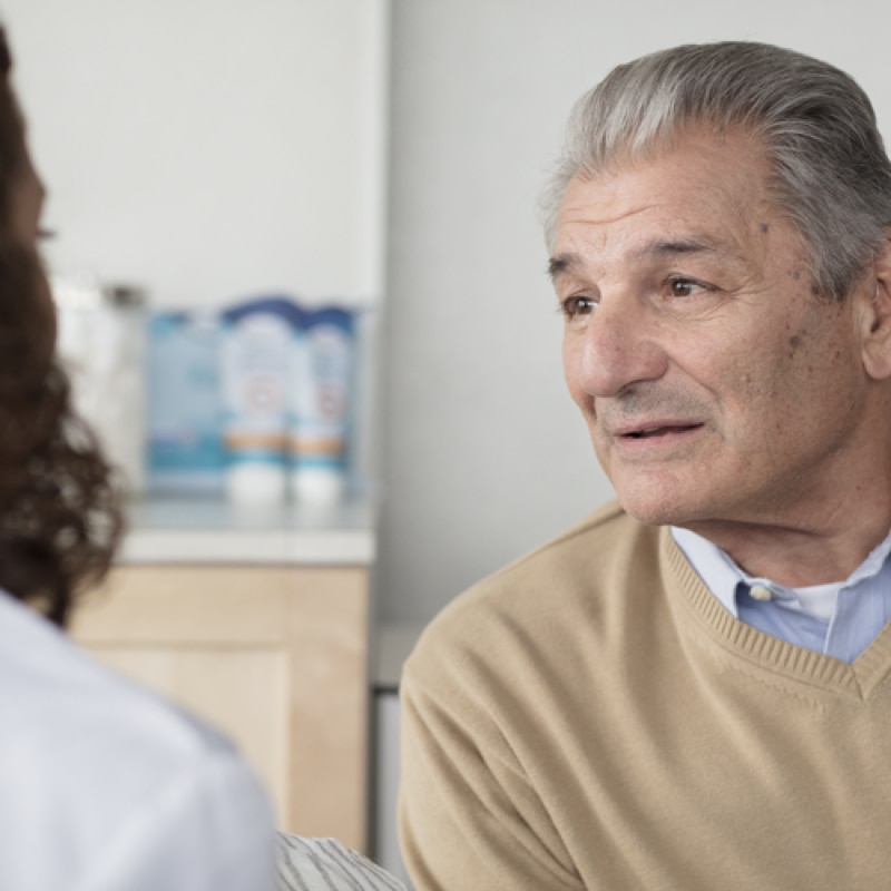 Ein älterer Bewohner spricht mit seiner Betreuerin in ihrem Büro.
