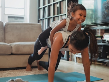 Mum working out at home with daughter on her back Mum working out at home with daughter on her back
