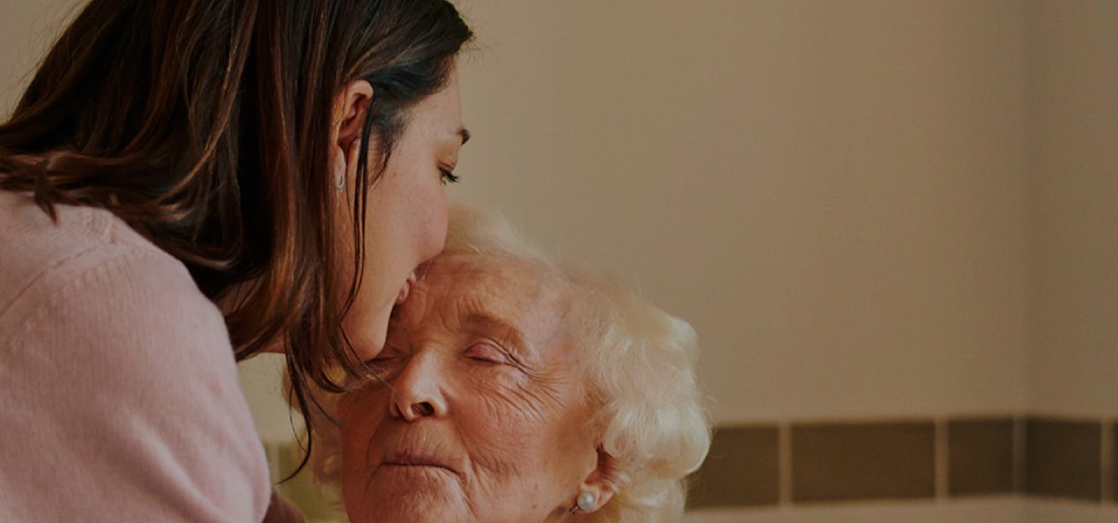 Younger woman kissing an older woman on the forehead