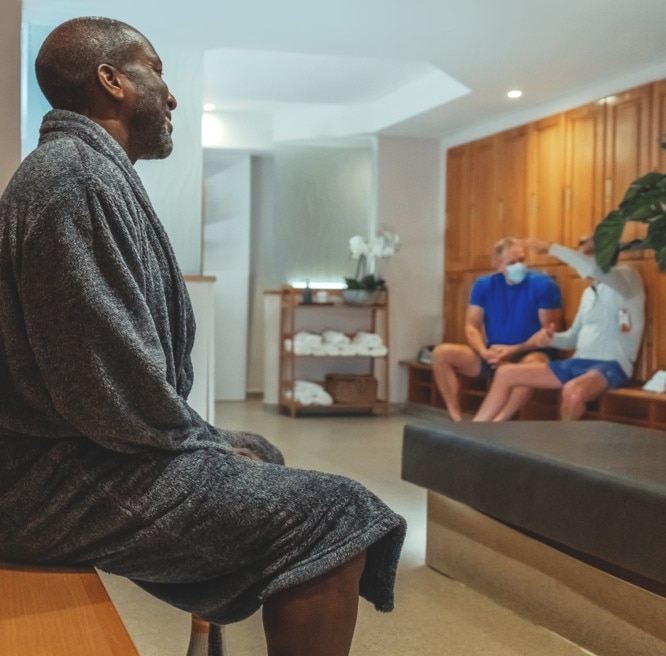 A man sat in a dressing gown in a male changing room