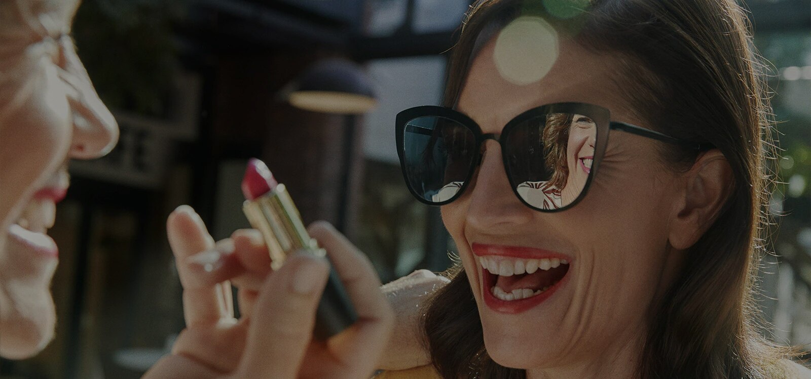 Mujer riéndose mientras que se pinta los labios