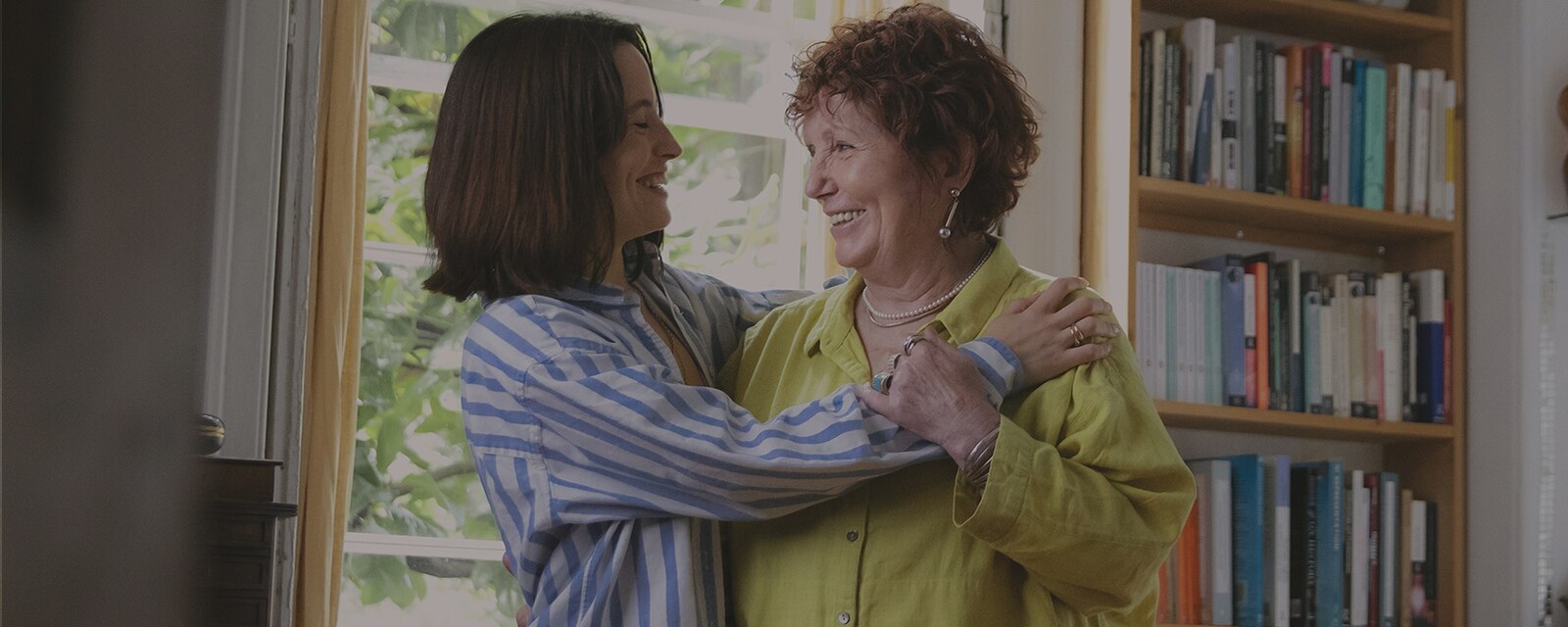 Mother and daughter hugging by a window