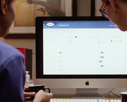 A nurse and a care home administrator look at a TENA Identifi dashboard on a computer screen.