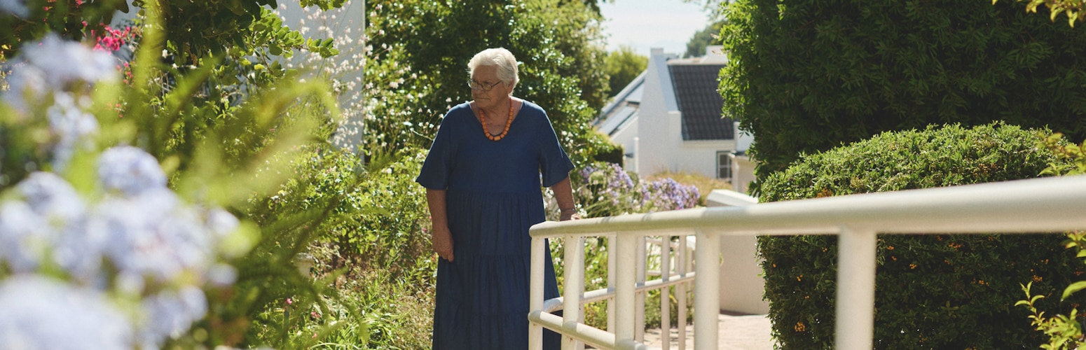 An elderly female nursing home resident walks in the garden of a nursing home on a sunny day 