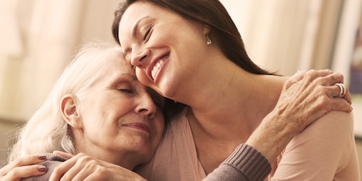 Younger woman and an older woman smiling in embrace
