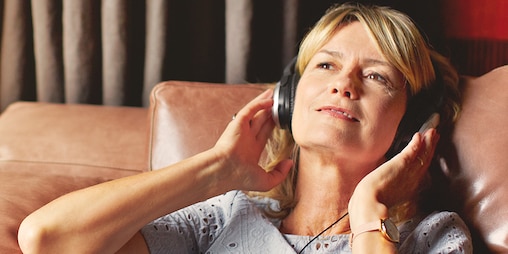 Vrouw die zich ontspant en naar muziek luistert – tips hoe u als verzorgende minder stress hebt