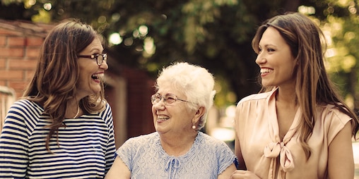 Femme âgée accompagnée de deux femmes plus jeunes dehors – comment le vieillissement affecte notre mobilité
