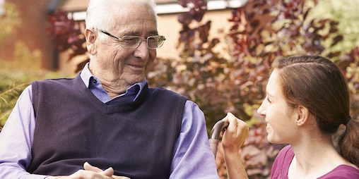 Starší muž sedí s mladšou ženou vonku – prečítajte si o skúsenostiach ostatných opatrovateľov