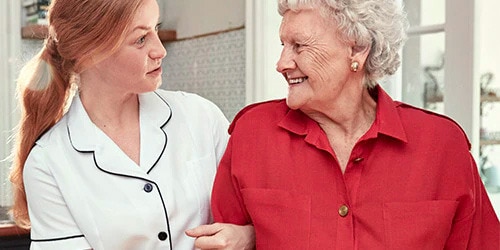 Nurse talking to a smiling elderly woman.