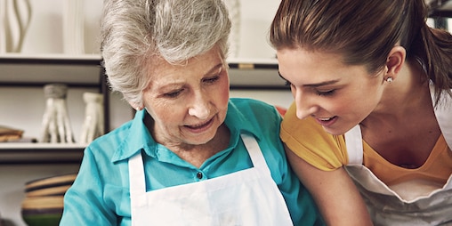 Elderly woman in an apron with younger woman in an apron