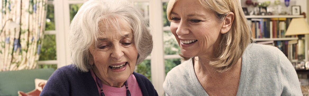 Mladá žena a starší žena se společně smějí – kde najít organizace poskytující podporu při péči