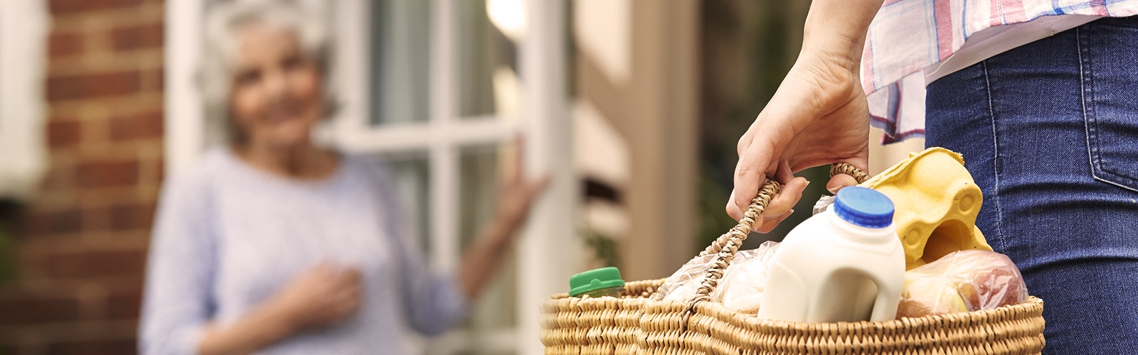 Young woman bringing an older woman groceries Young woman bringing an older woman groceries