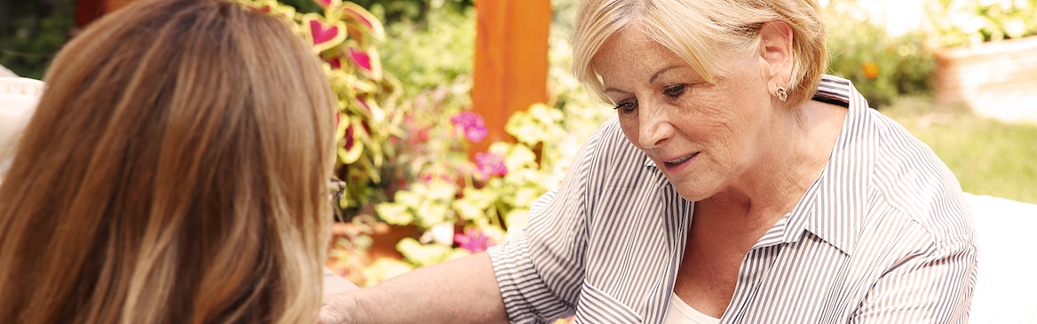 Starsza kobieta siedząca z młodszą – niedrogie sposoby opieki nad bliskimi