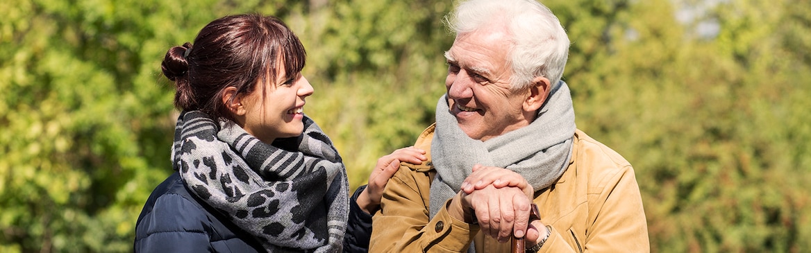 Senhor mais velho sentado no exterior com senhora mais jovem – apoio financeiro para cuidadores