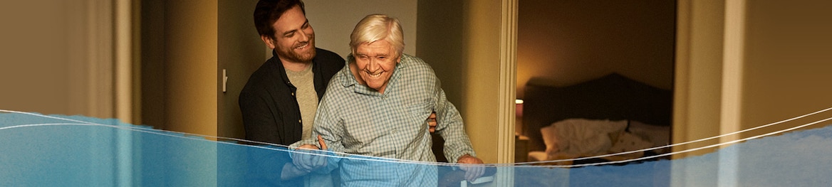 Pflegende hilft einem alten Mann in sein Zimmer