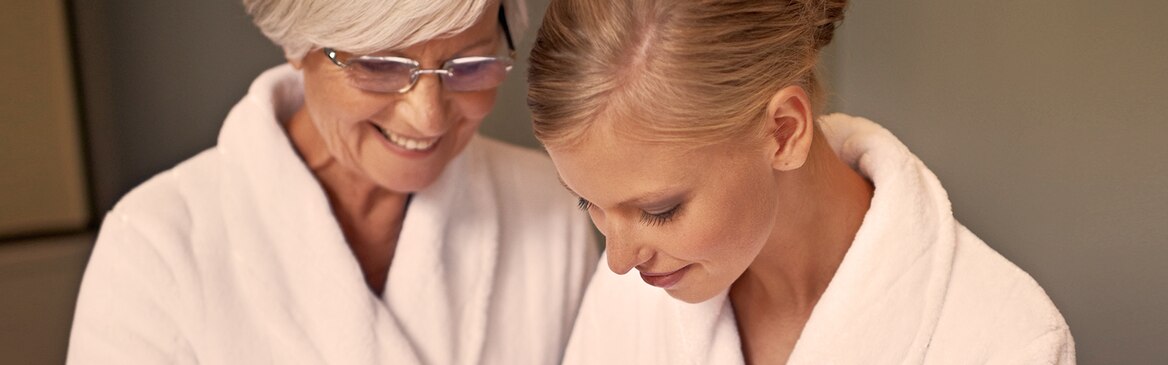 Starsza kobieta pielęgnuje swoją skórę w towarzystwie młodszej – zapewnienie bliskiemu właściwej higieny 