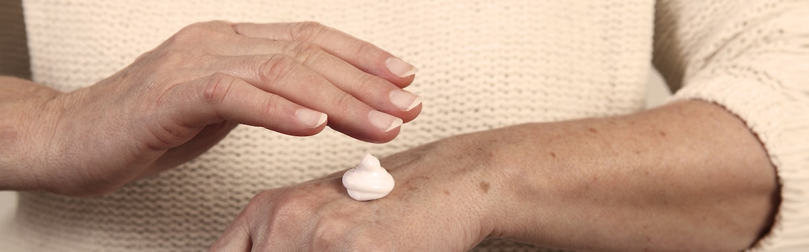 Ältere Frau trägt eine Feuchtigkeitscreme auf – bewahren Sie die Hautgesundheit Ihres Angehörigen