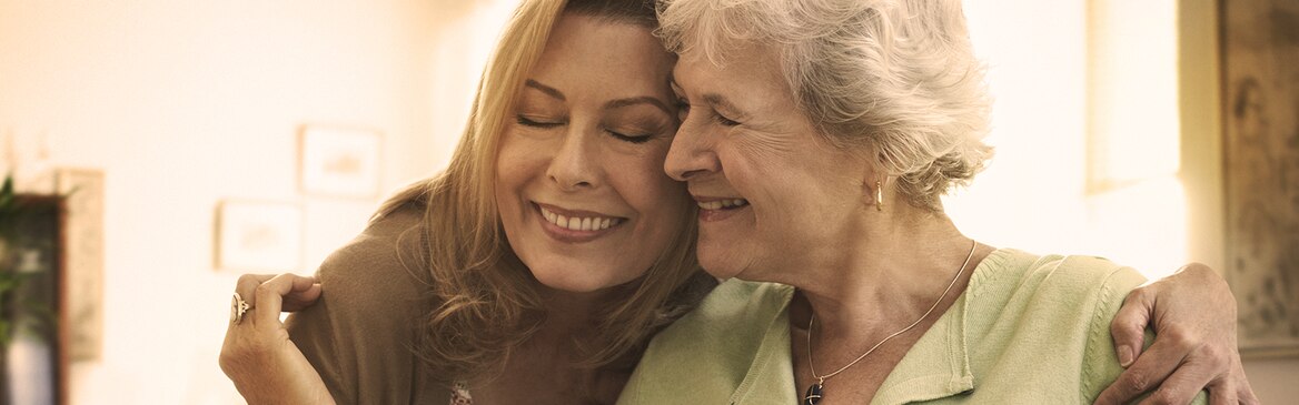 Žena v seniorskom veku objíma mladšiu ženu – príprava na úlohu opatrovateľa