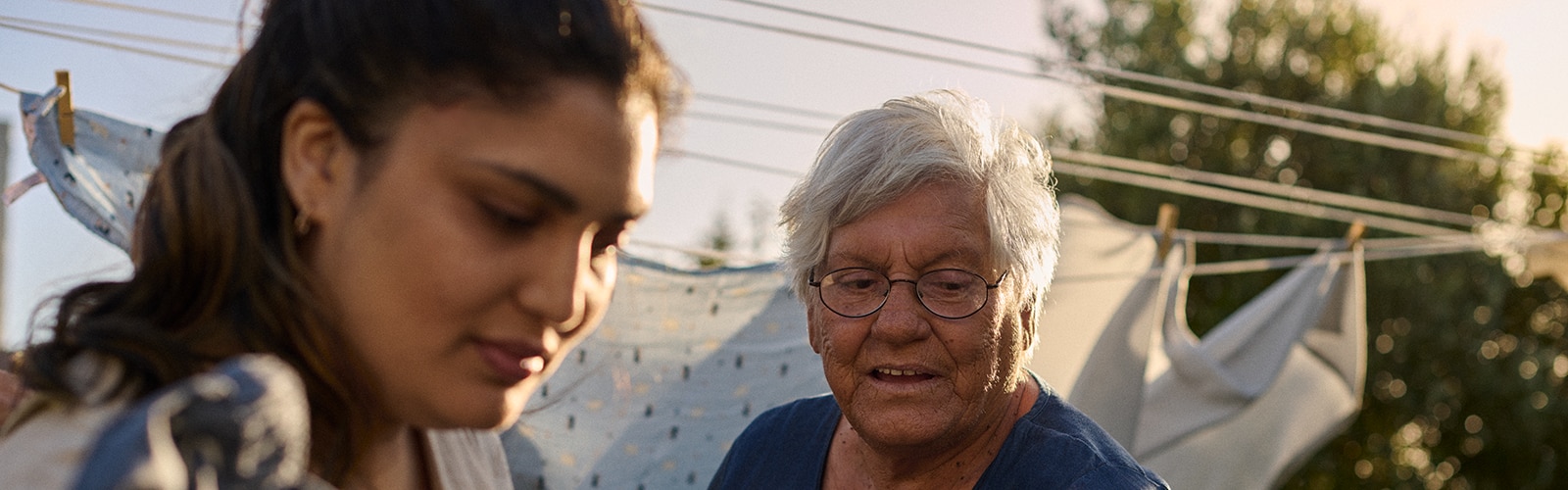 Elderly woman and younger woman hanging laundry outdoors