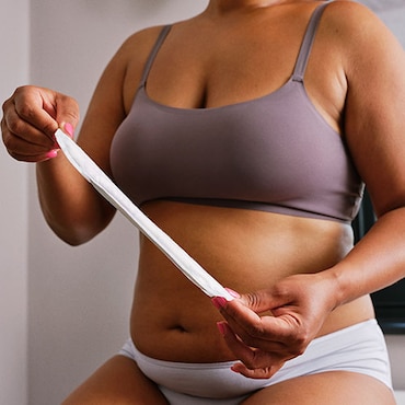 A woman holding a TENA Discreet pad in front of her