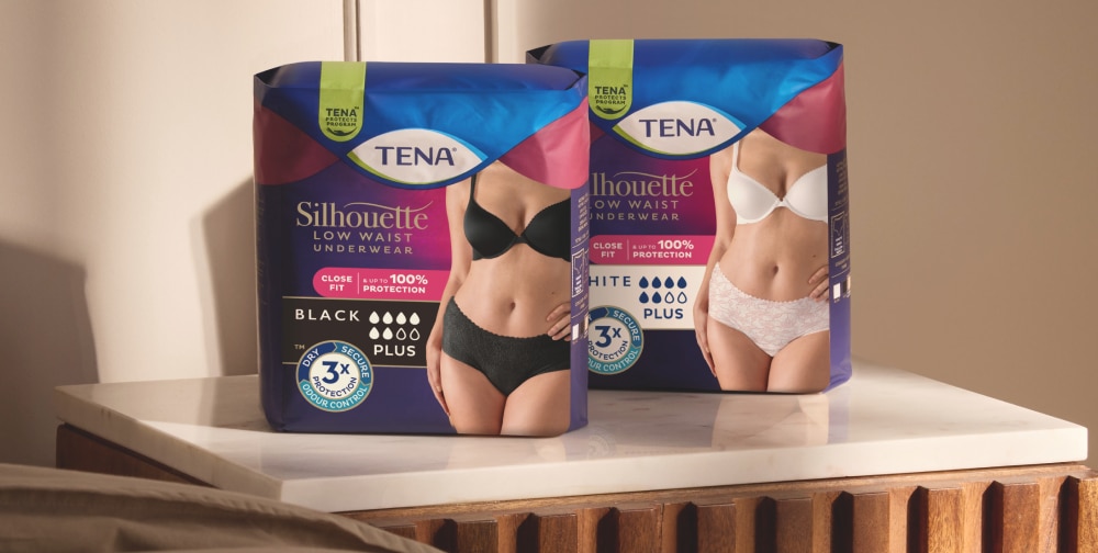 De productverpakking van TENA Silhouette Pants in zwart en wit op een tafel.
