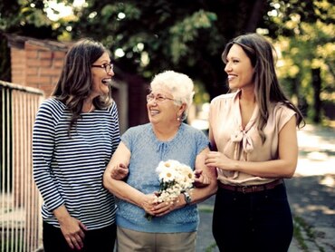 Two younger women and one older woman walking down a street.