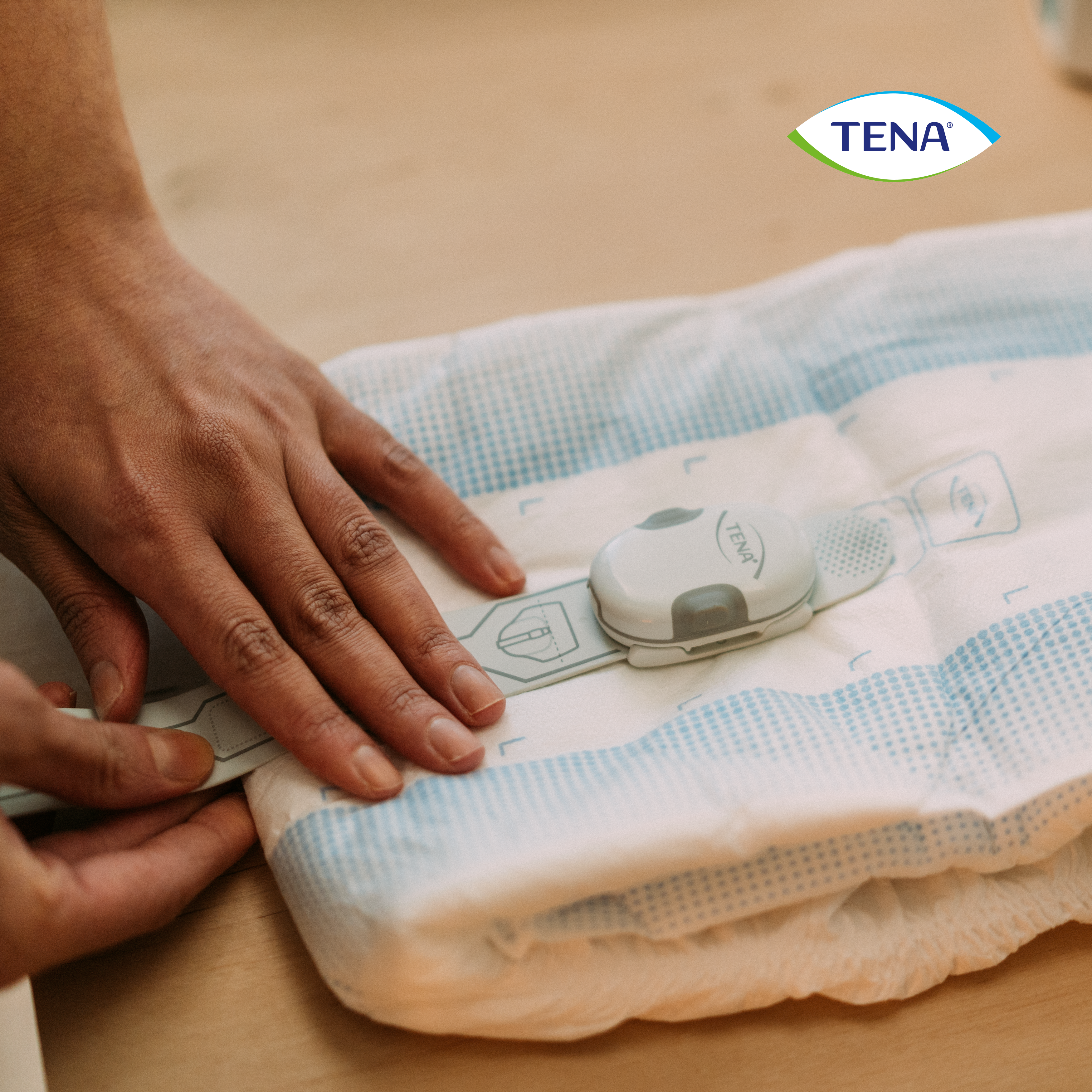 Der TENA SmartCare Change Indicator™ besteht aus zwei Teilen: einem Sender und einem Sensorstreifen. Beide werden an der Außenseite des absorbierenden TENA-Inkontinenzprodukts angebracht.