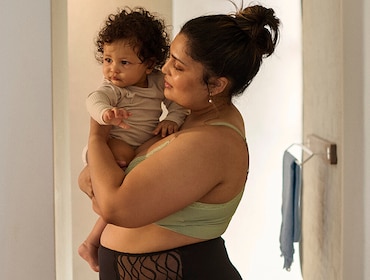 Mum holding baby while wearing TENA silhouette washable underwear