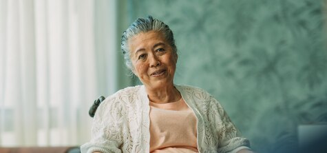 Eine ältere Frau sitzt in ihrem Wohnzimmer