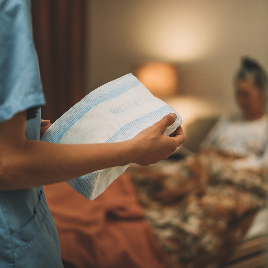 A professional caregiver holds a TENA absorbent product.