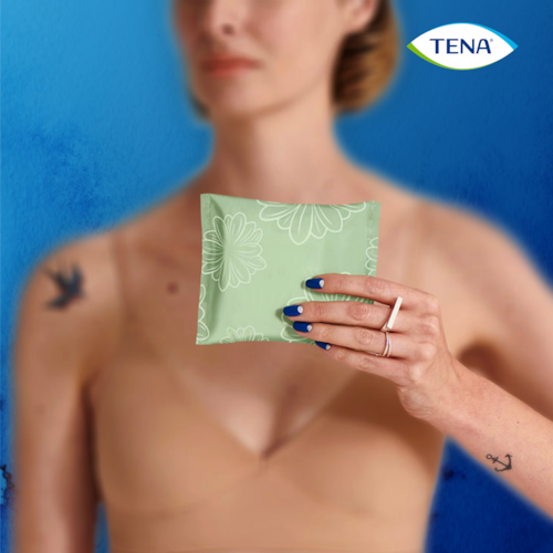 Hält eine einzeln verpackte Inkontinenzeinlage von TENA Discreet Mini in der Hand