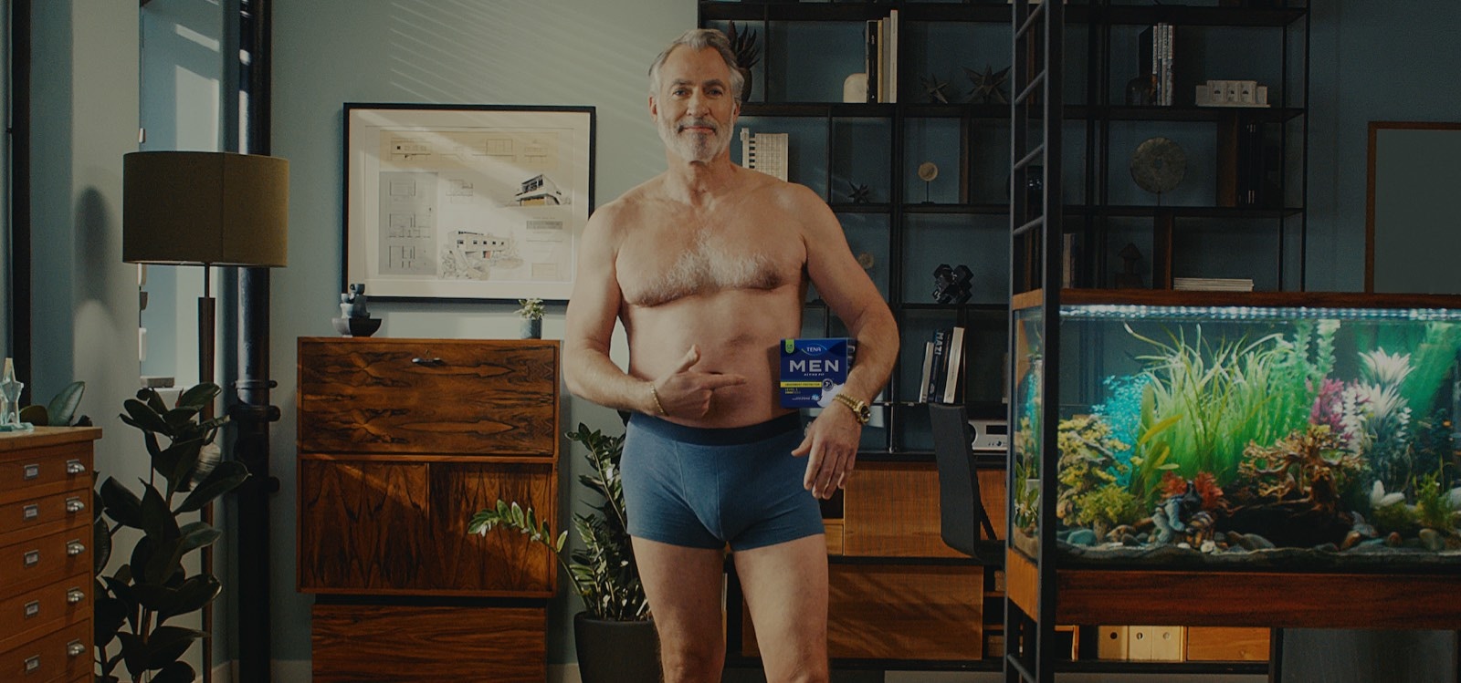 Un hombre mayor de 50 años se muestra seguro y relajado posando con la ropa interior TENA Men. 