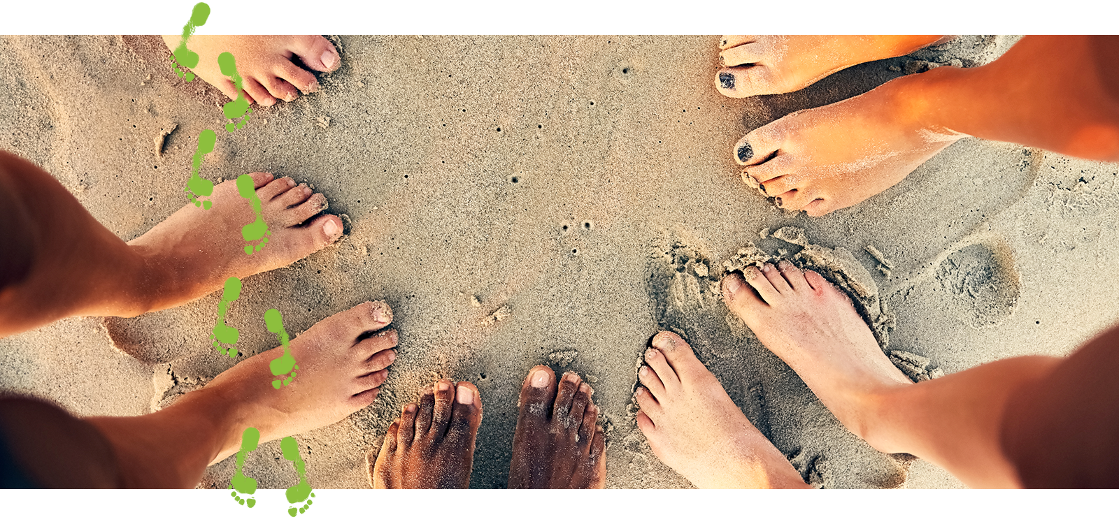 Bare feet of a group of people in a circle on a sandy beach 