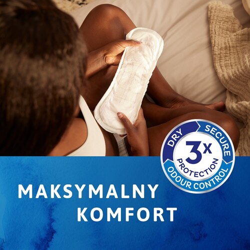 Kobieta trzymająca produkt TENA, zapewniający maksymalny komfort, z widocznym logo i hasłem reklamowym.