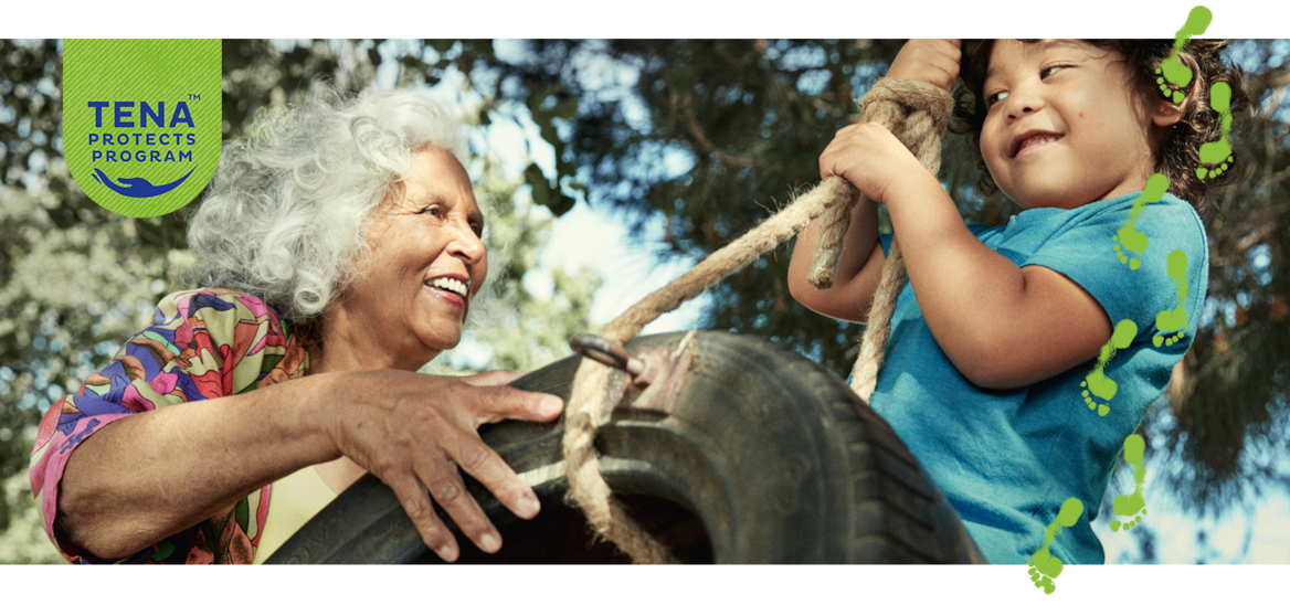 Une femme âgée souriante pousse un jeune garçon sur une balançoire pneu. 