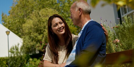 Älterer Mann sitzt neben jüngerer Frau – nützliche Tipps für Einsteiger in die Pflege