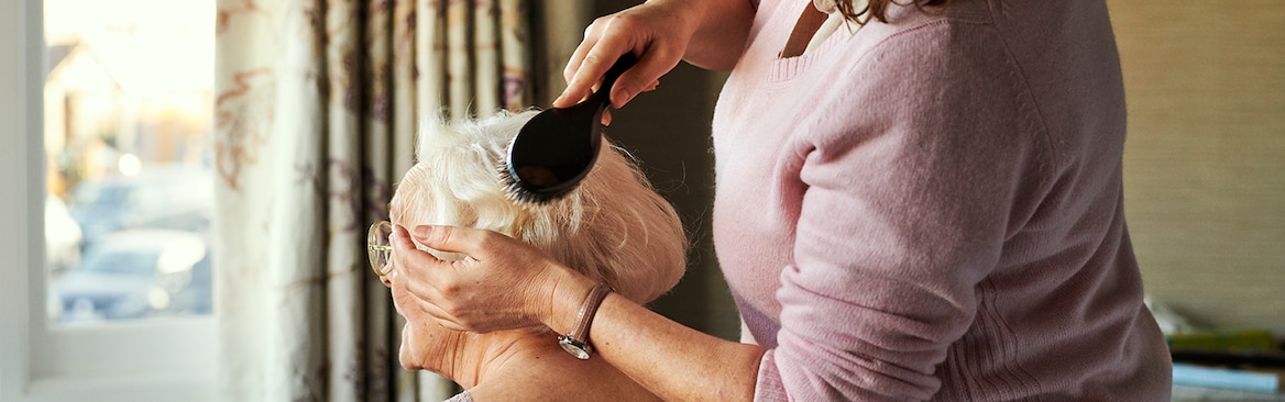 Carer brushing elderly woman's hair