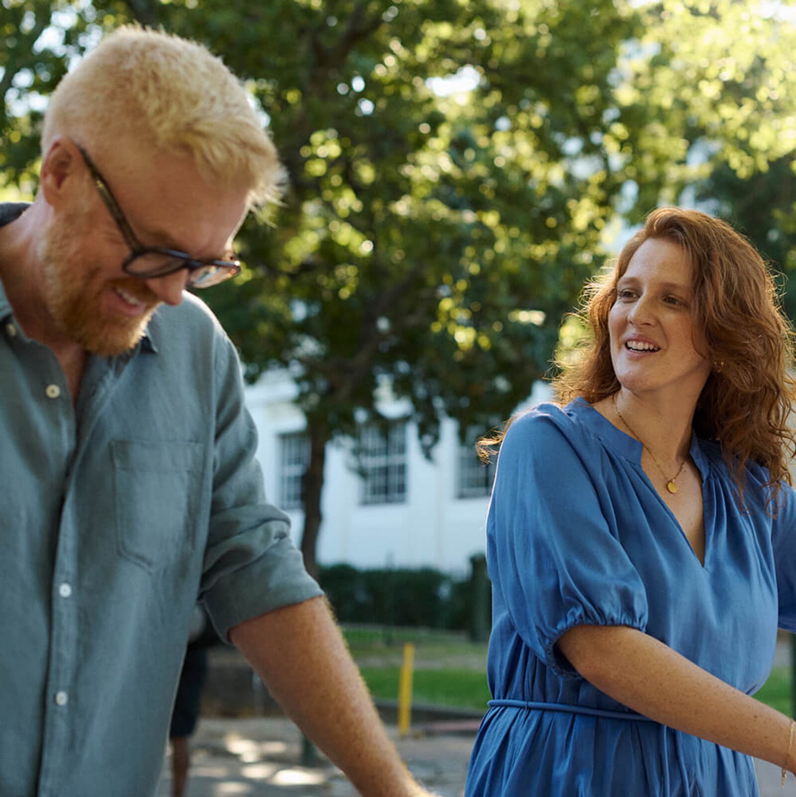 A man and woman walking in the park laughing together